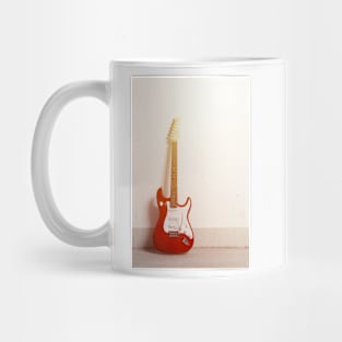 Red electric guitar standing left against white raw wall Mug